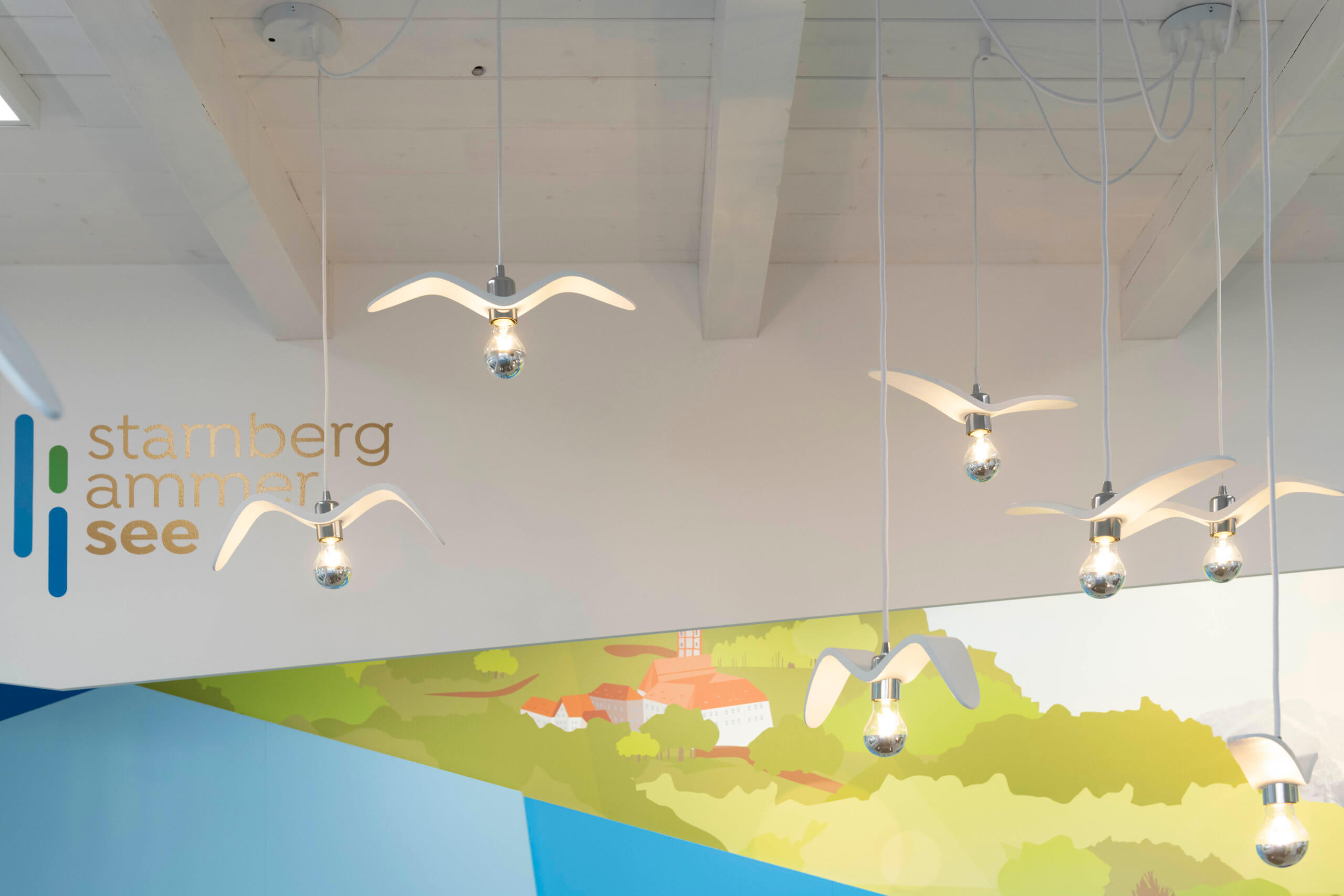 Das Bild zeigt die Deckenlampen der Touristeninformation in Herrsching am Ammersee. Die Lampen sind in ihrer Form den Seemöven nachempfunden.