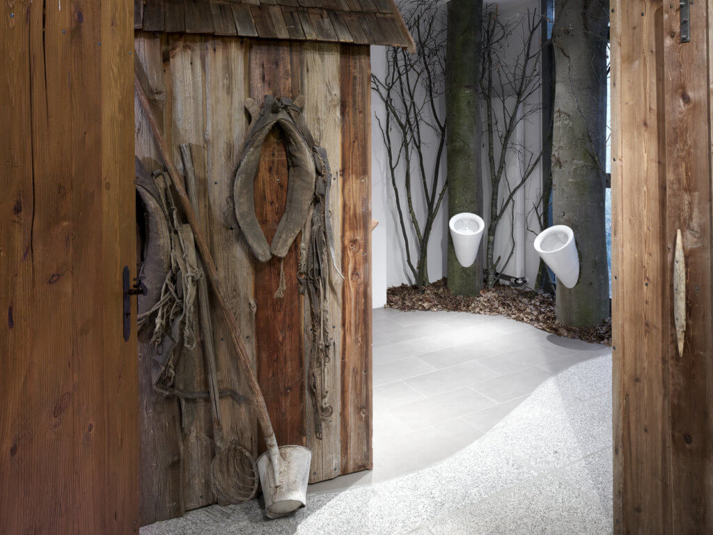 Ausgefallene Herrentoilette mit Urinalen an Baumstammimitaten.