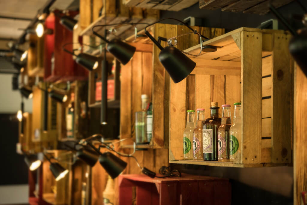 Das Bild zeigt ein Weinflaschenregal aus alten Weinkisten im Oberstdorf Hostel.