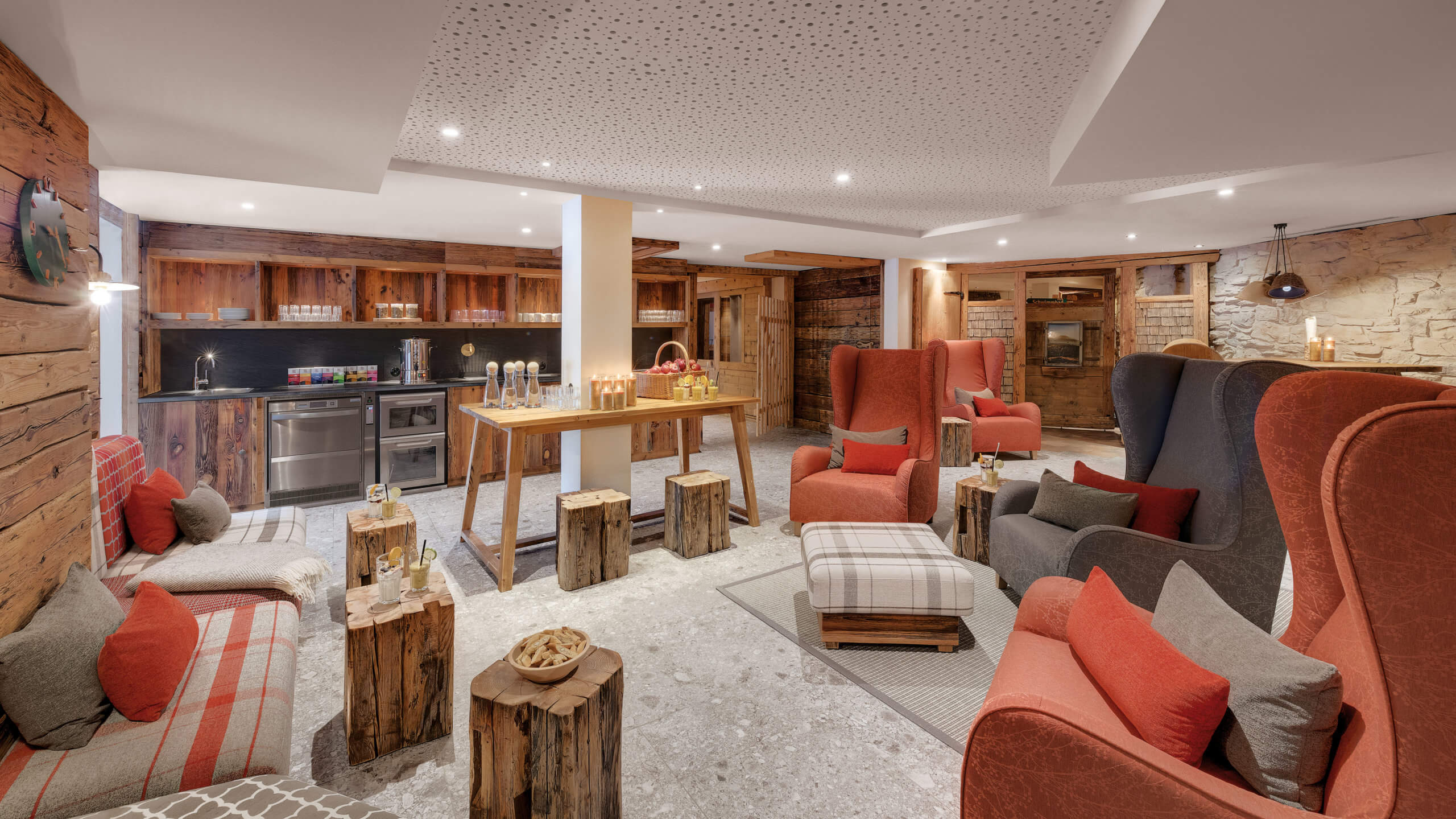 DasBild zeigt einen Aufenthaltsraum mit Bar im Hotel Oberstdorf mit vielen fabigen Sesseln und einem Kamin.
