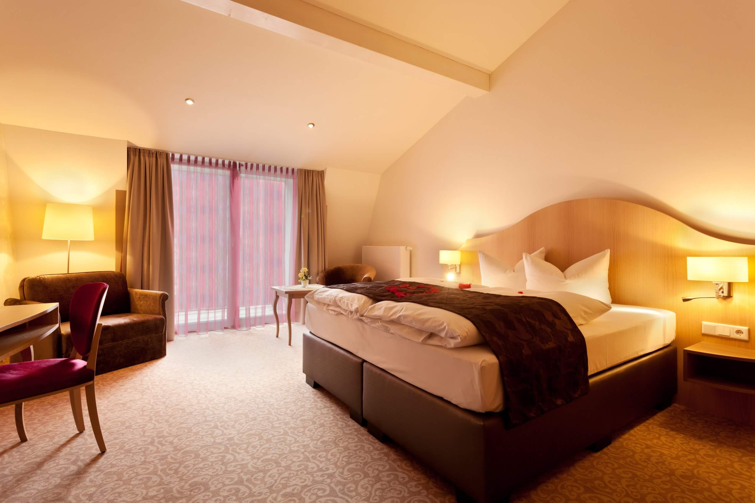 Das Foto zeigt eine Suite im Hotel Villa Ludwig Hohenschwangau - mit großen Doppelbett und breiter Fensterfront.