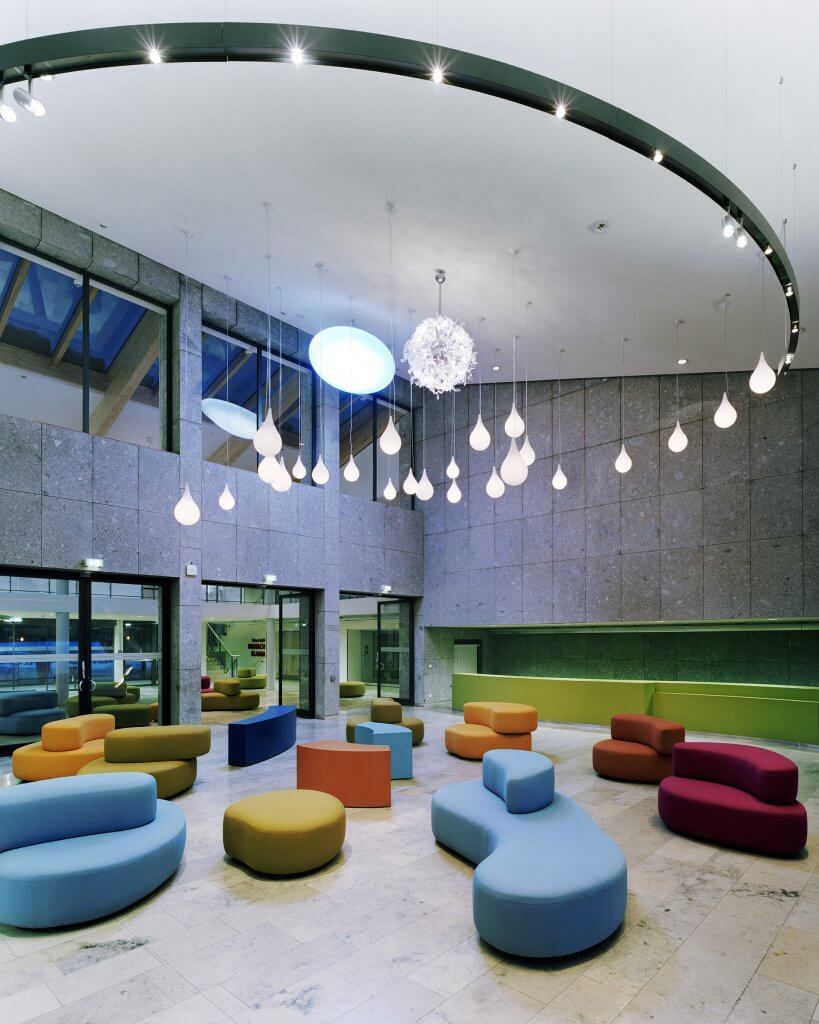 Foyer mit farbigen Sitzmöblen im Kurhaus Oberstdorf. Überdimensionla große kreisrunde Dekcenleuchte.