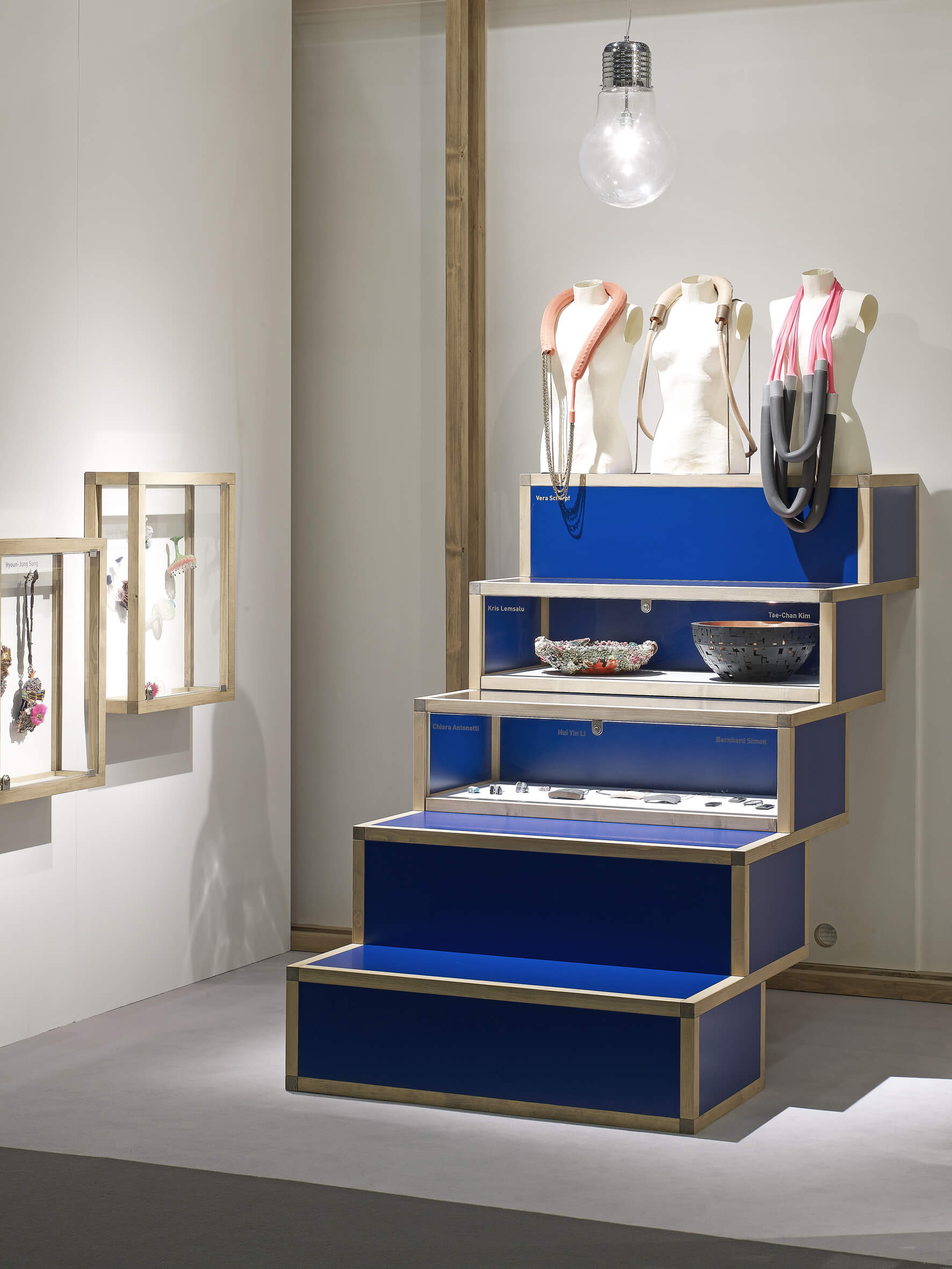 Dunkelblaues Ausstellungsmobiliar mit treppenförmig angeordneten Präsentationsflächen.