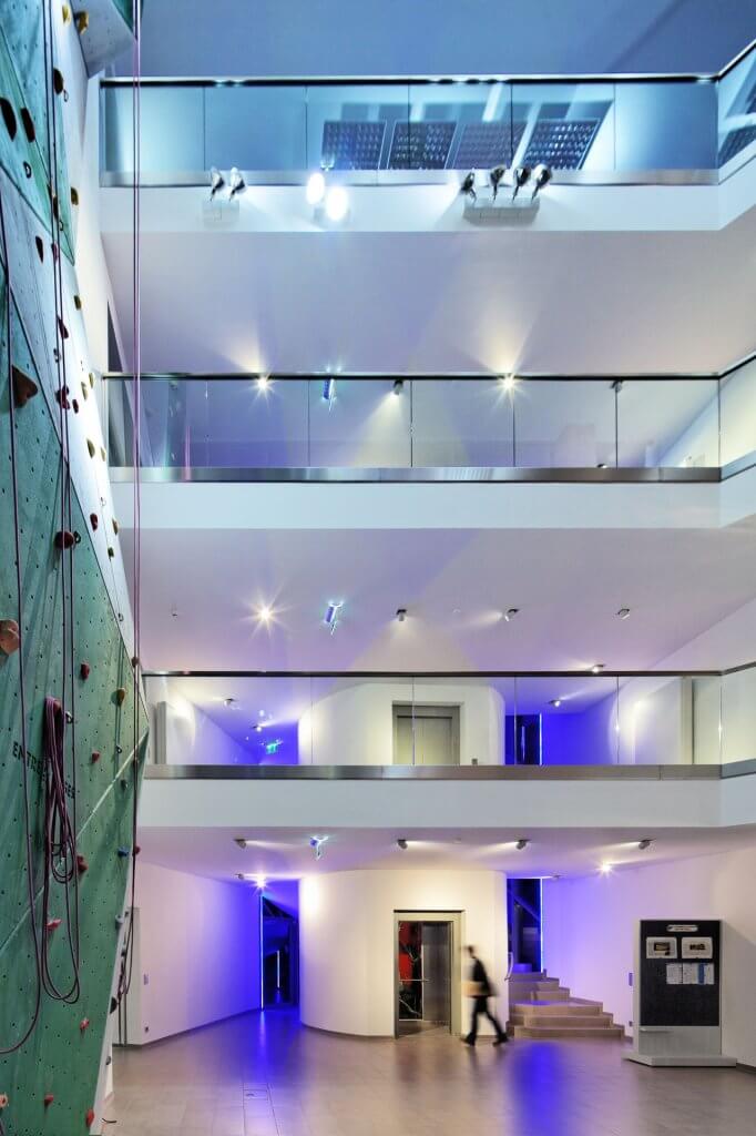 Modernes Bürogebäude mit Glasverkleidungen im Treppenhaus und Kletterwand als Sportelement für die Mitarbeiter.